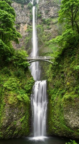 A generic waterfall image with an arch bridge in foreground to potray the serene and calm nature and environment which is tranquil.